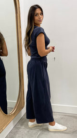 Woman in navy blue outfit standing in front of a mirror.
