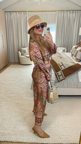 Woman in a patterned outfit taking a mirror selfie in a stylish room.