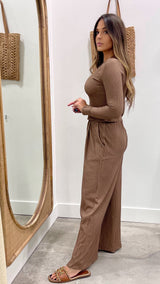 Woman in a brown ribbed jumpsuit standing in front of a mirror.