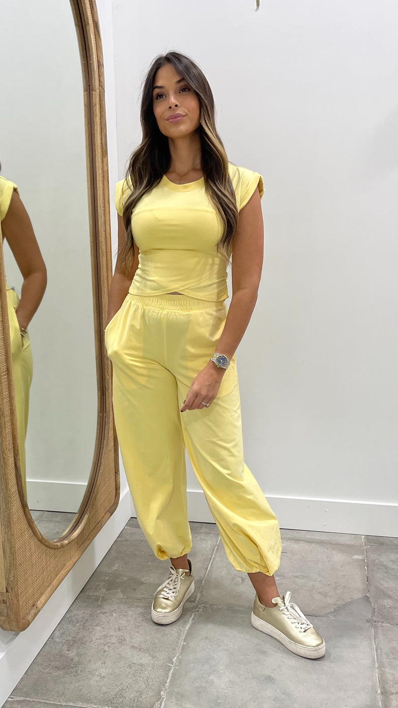 Woman in a yellow outfit standing in front of a mirror.
