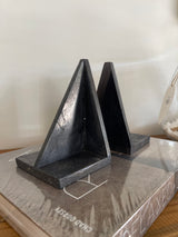 Black metal bracket on a white surface with a blurred background