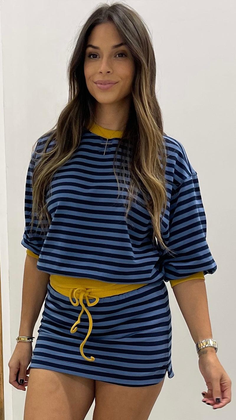 Woman wearing a blue and yellow striped outfit with a plain background