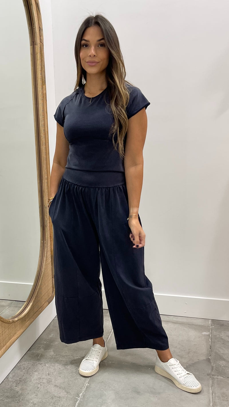 Woman wearing a navy outfit with wide-leg pants standing in front of a mirror.