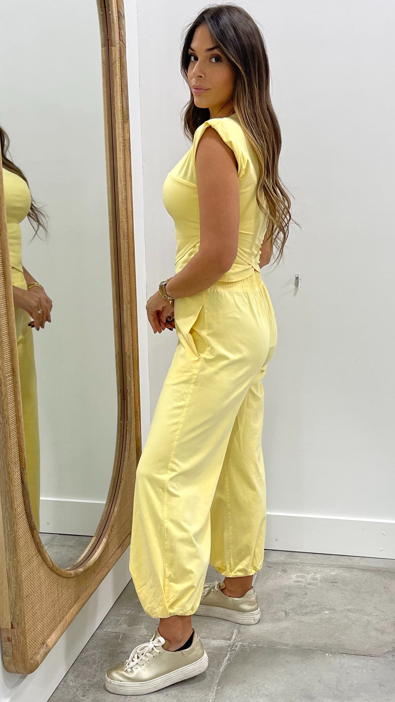 Woman in a yellow jumpsuit standing in front of a mirror.