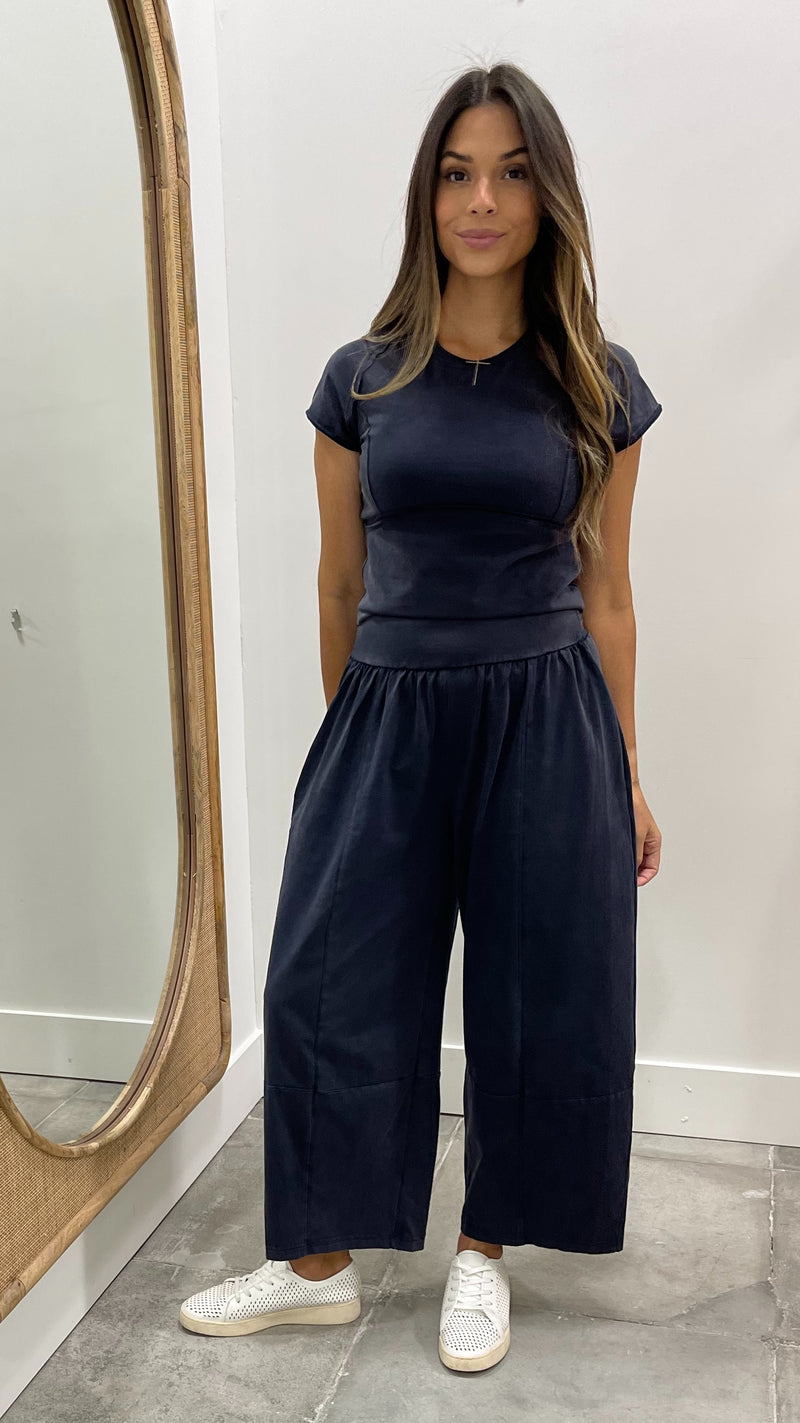 Woman wearing a navy outfit standing in front of a mirror.