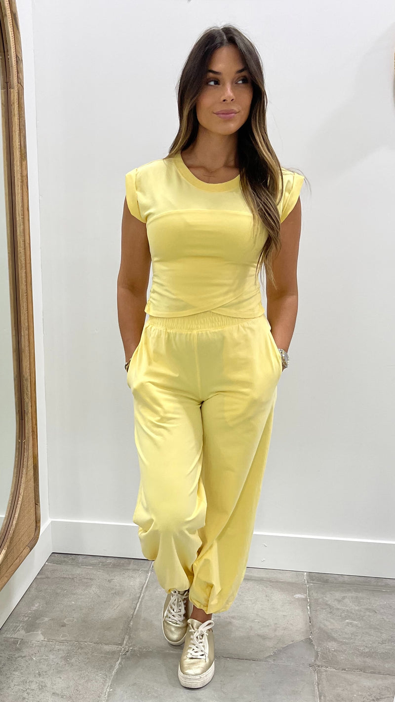 Woman wearing a yellow outfit standing in front of a mirror.