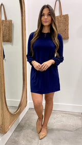 Woman wearing a blue dress standing in front of a mirror.