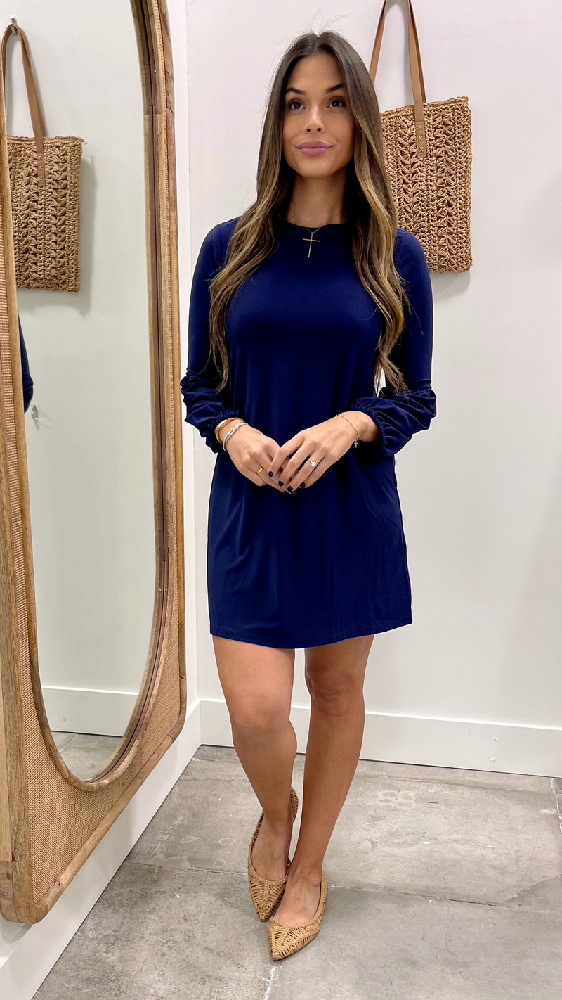 Woman wearing a blue dress standing in front of a mirror.
