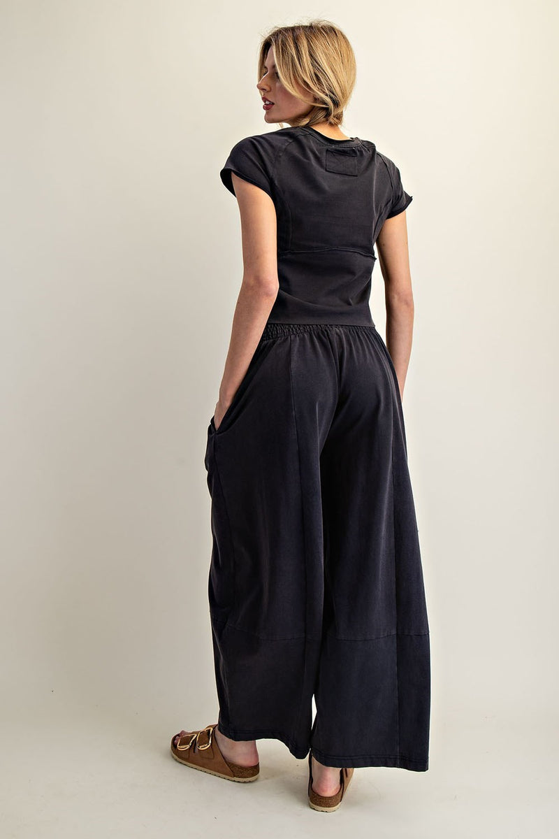 Woman wearing a black outfit with wide-leg pants on a plain background